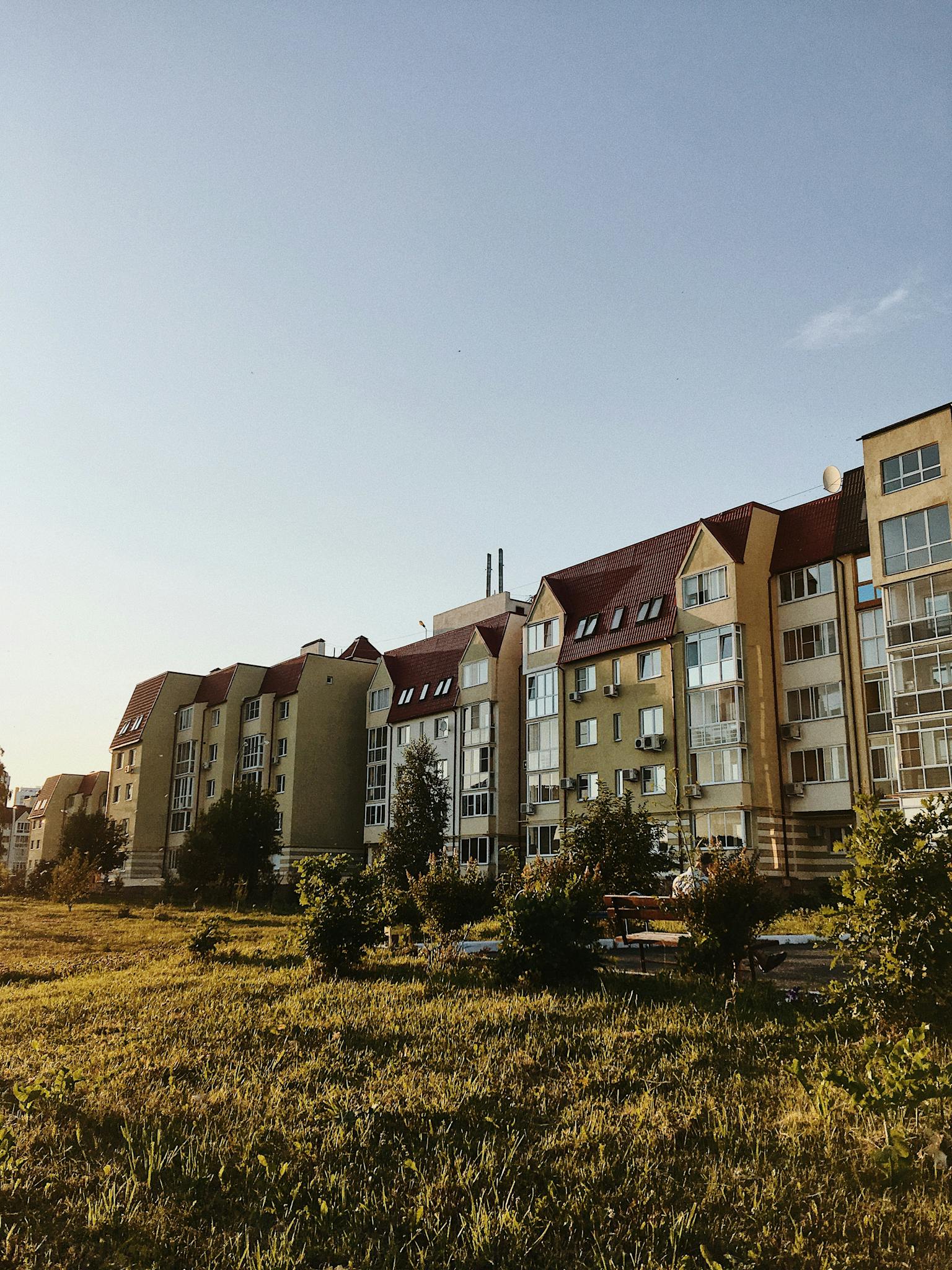 Contemporary apartment buildings with a grassy area and sunny ambiance.