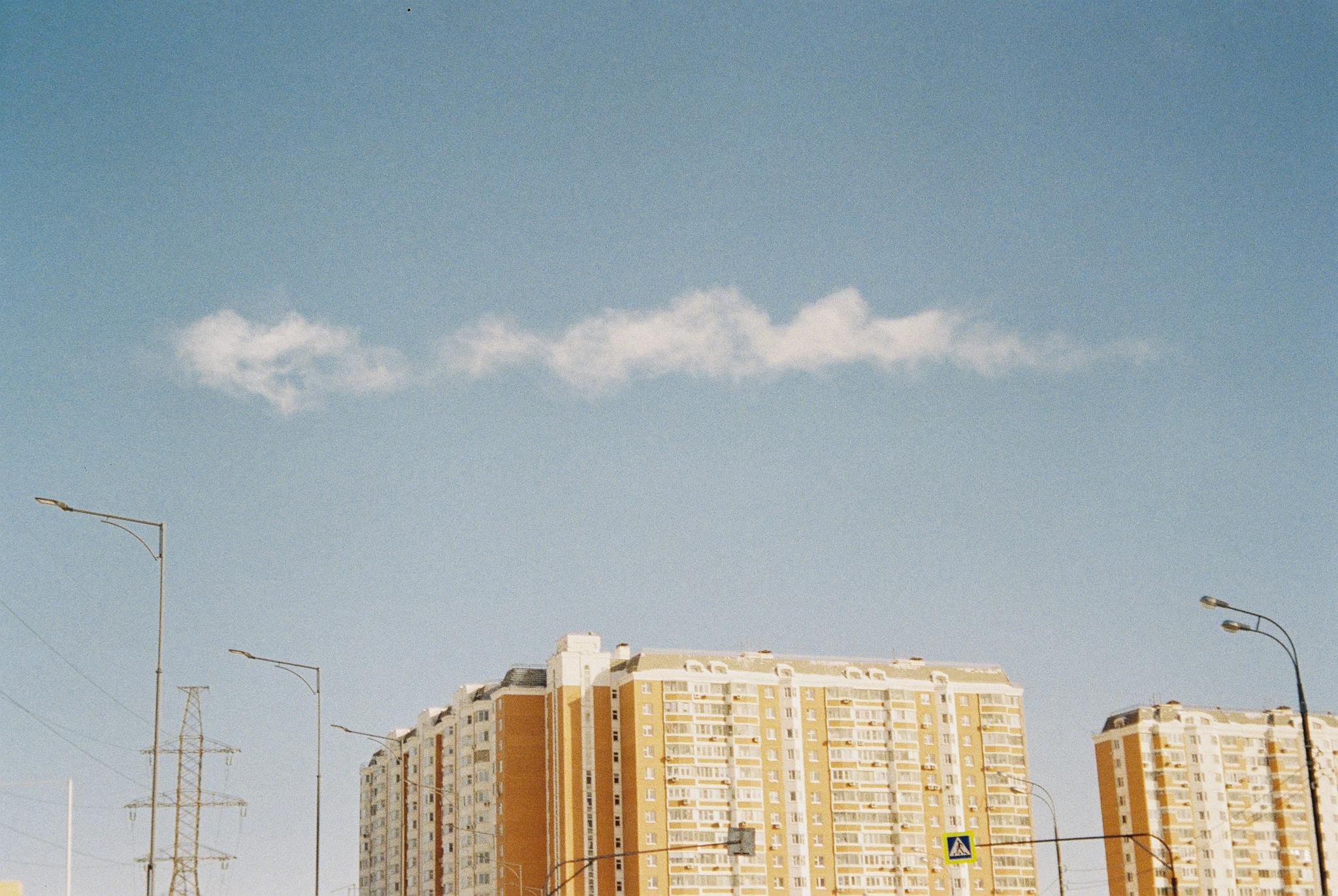 Low angle view of modern condominium against a clear blue sky, showcasing urban architecture.
